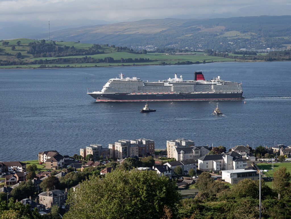 The liner Queen Anne photographed leaving Greenock accompanied by two tugs.